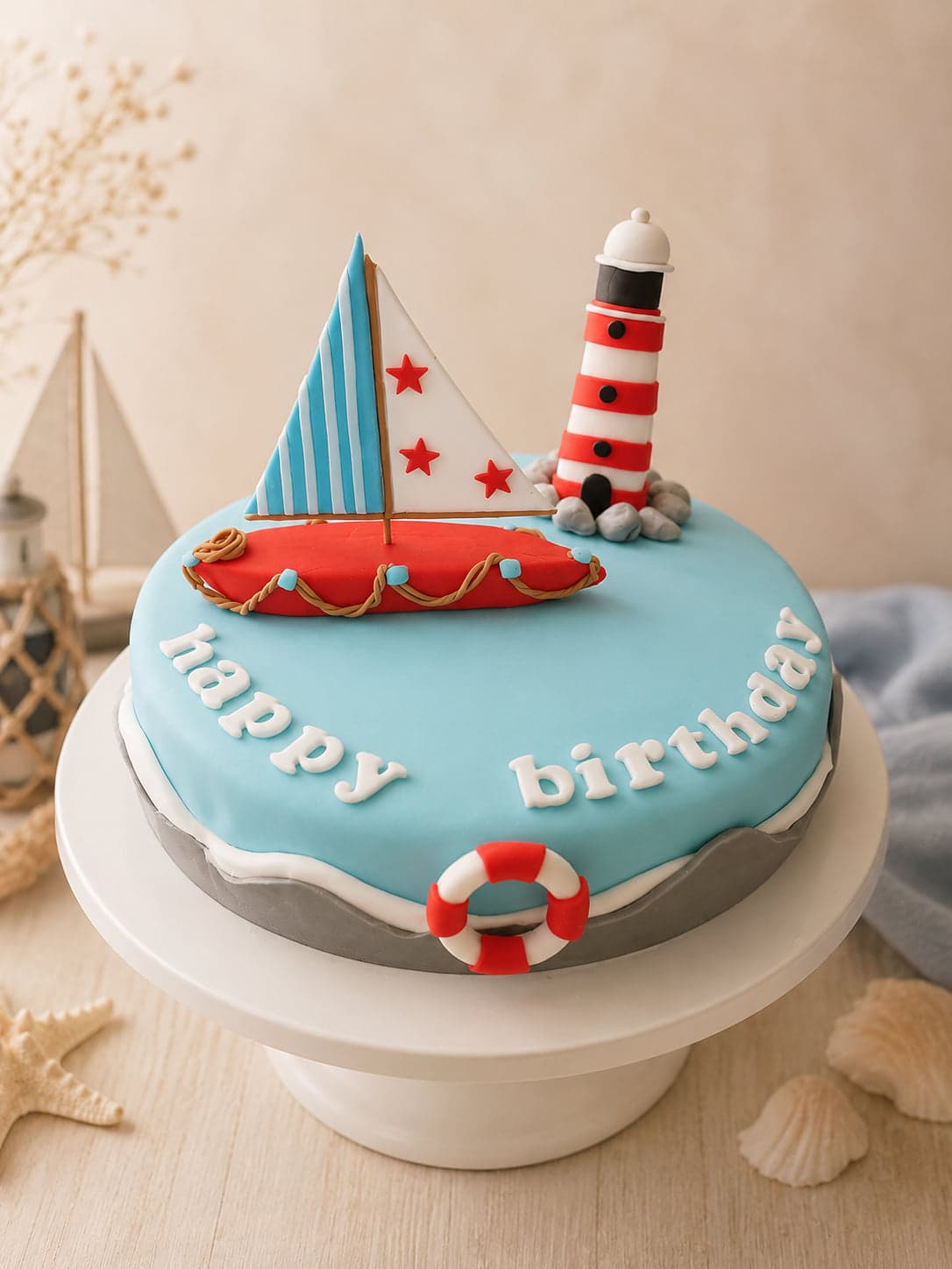 Fondanttaart met een zeilboot, een vuurtoren en een reddingsboei in rood, wit en lichtblauw