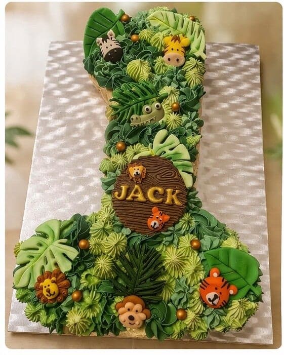 Cijfertaart in de vorm van een 1, jungle-thema met groene toeven en dierenkopjes en de naam Jack
